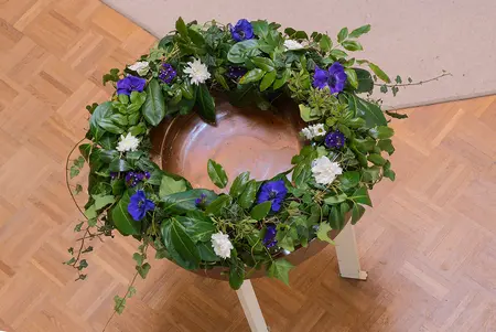 Die Taufschale in der Johann-Sebastian-Bach-Kirche geschmückt mit einem Blumenkranz