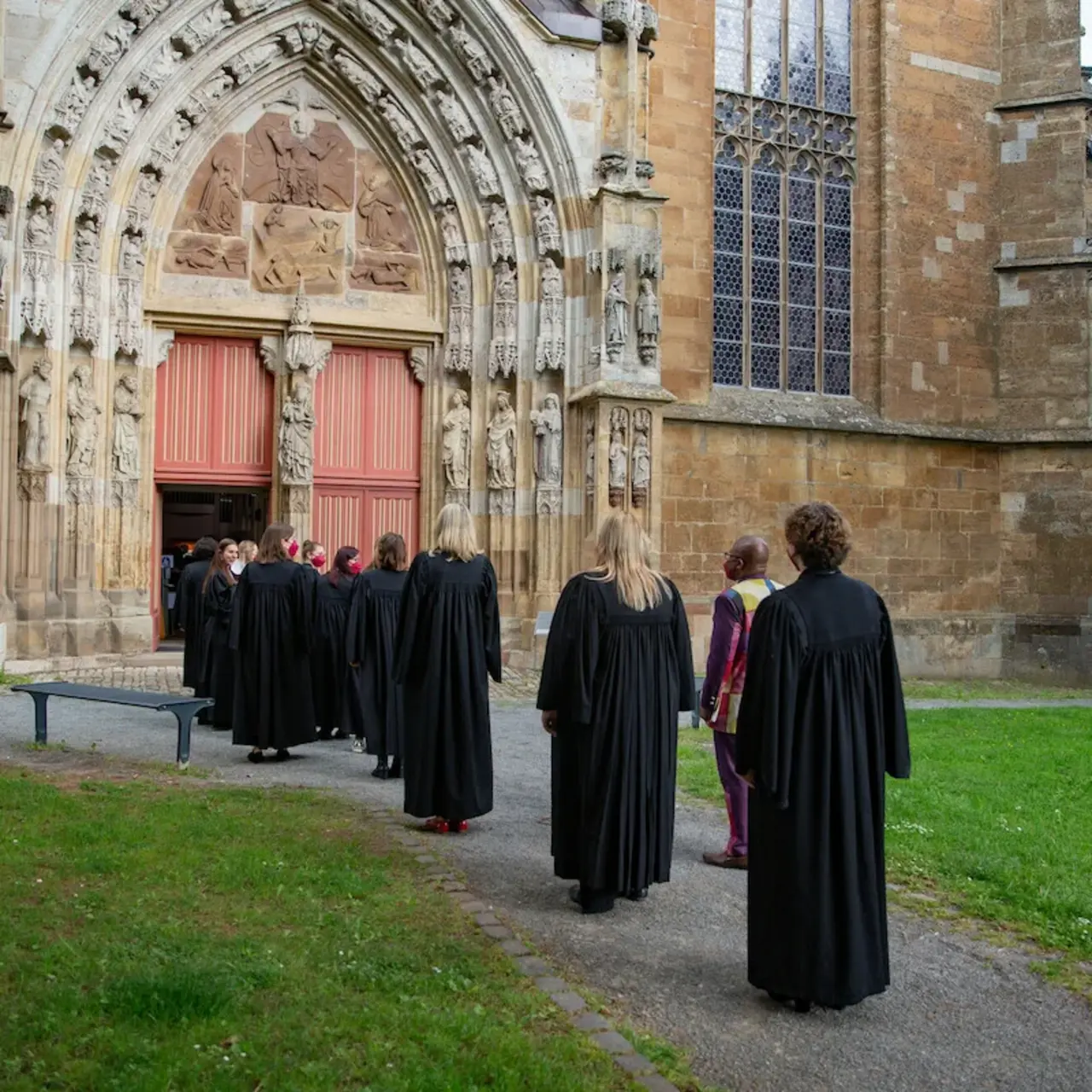 Einzug - MIt einem feierlichen Ordinationsgottesdienst in der Kilianskirche in Korbach wurden am Sonntag den 22.Mai 2022 9 Pfarrer*innen in den Dienst der Evangelischen Kirche von Kurhessen-Waldeck durch BIschöfin Dr. Beate Hofmann eingeführt. Pfarrer*innen stehen auf dem Weg vor dem Tor der gotischen Kilianskirche in Korbach.