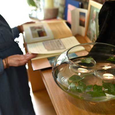 Auf einem Altar für eine Verstorbene im Hospiz steht eine mit Wasser gefüllte Vase, in der zwei Teelichter und Blätter schwimmen.